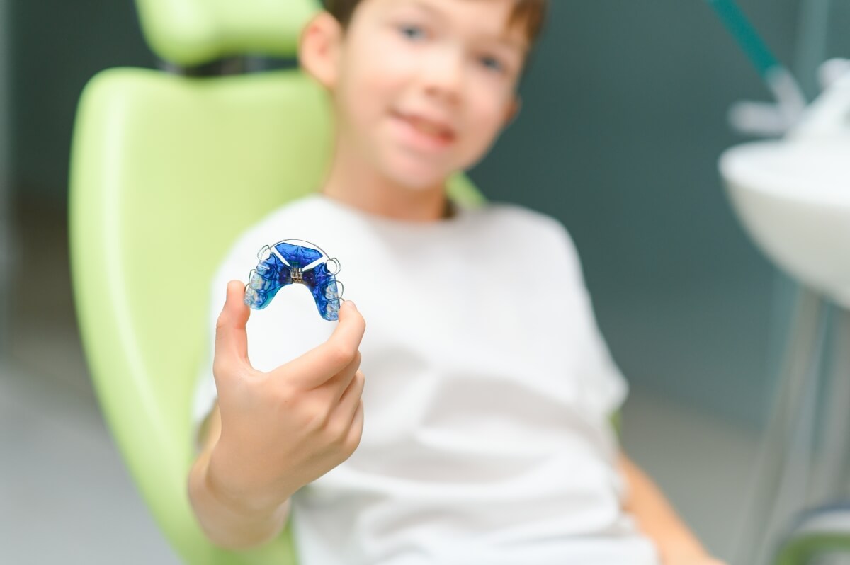 Dziecko trzymające aparat ortodontyczny jako część przygotowania dziecka do aparatu ortodontycznego.