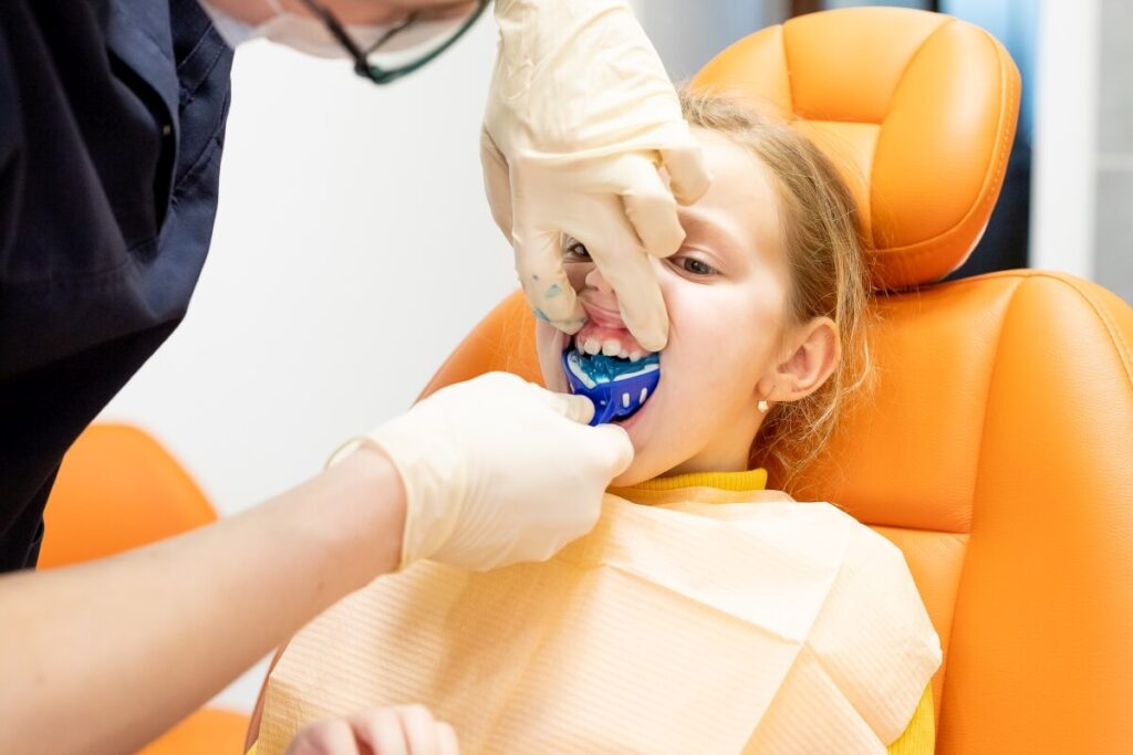 Dziecko przechodzi proces leczenia w ortodoncji dziecięcej podczas wizyty u dentysty.