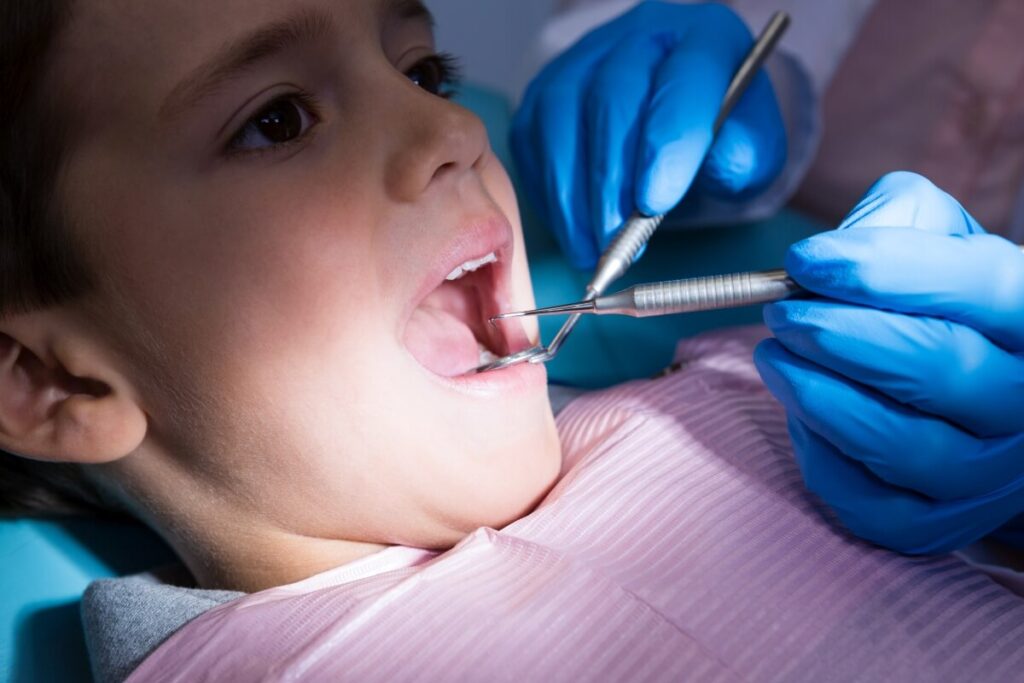 Dentysta leczący dziecko, co podkreśla zalety podtlenku azotu w leczeniu dzieci.