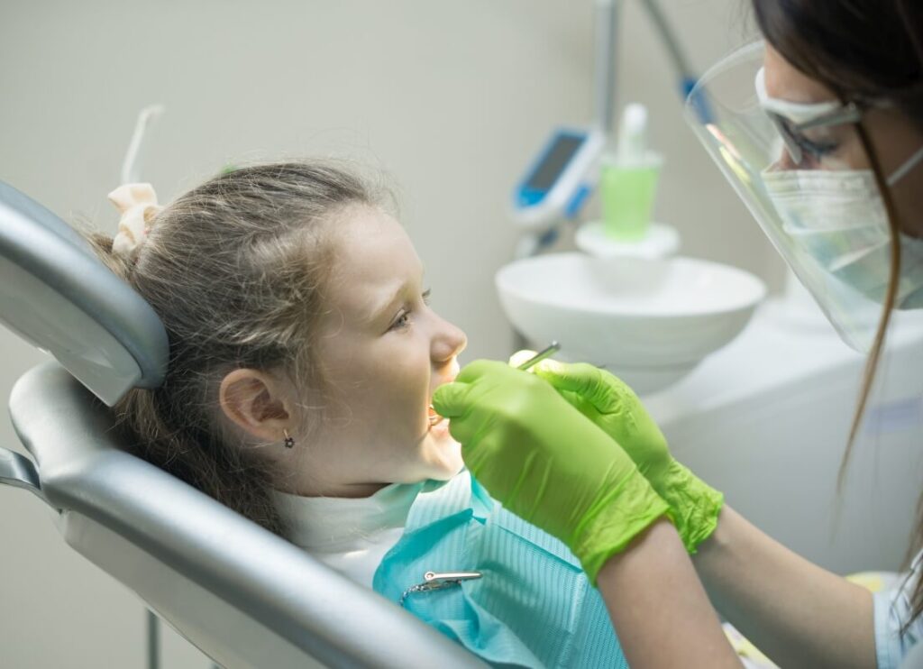 Dentysta prowadzi przygotowanie dziecka do leczenia stomatologicznego.