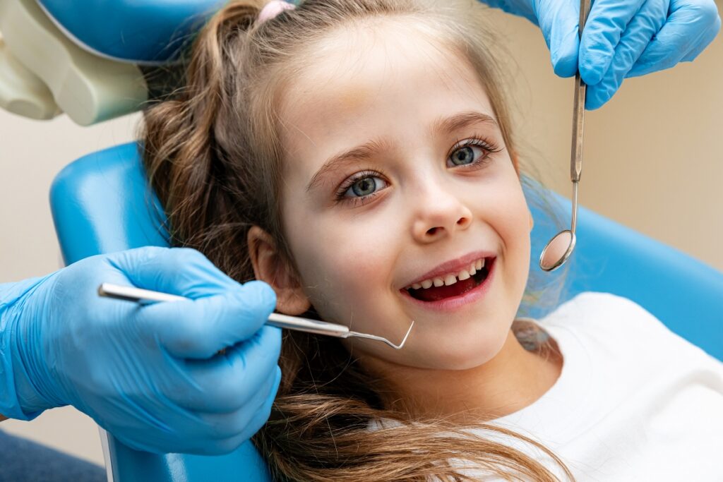 Dziewczynka u dentysty podczas wizyty, która jest częścią profilaktyki stomatologicznej dla dzieci.